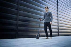 shot-young-handsome-man-standing-by-his-electric-scooter-street_342744-408